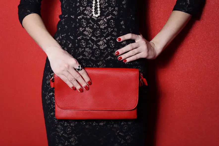 ผู้หญิงในชุดเดรสกำลังถือกระเป๋า Clutch Bag สีแดง